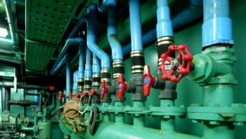 Focus on red gate valve on foreground with pipelines